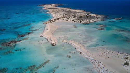 Overtourism, tourists on the beach, parasols, A peninsula with a sandy beach jutting out into the