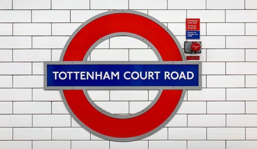 Tottenham Court Road sign on the London Underground against a background of white tiles with a red
