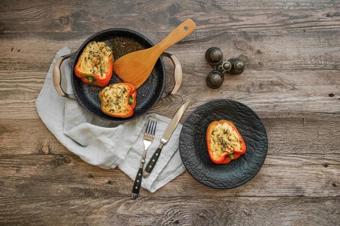 Overhead view of roasted bell peppers stuffed with goat cheese and mozzarella on wooden table