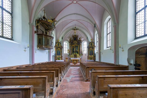 Parish church of St. Sebastian, interior with wooden benches and a central altar, high Gothic