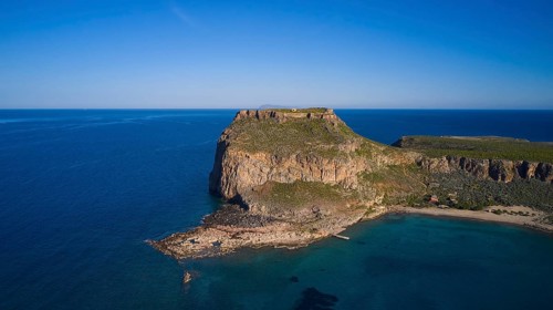 Drone shot, Rocky cliff coast with neighbouring beach and clear blue sky over the wide ocean,