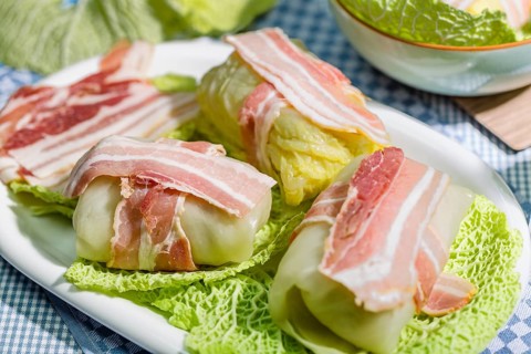 Preparation of savoy cabbage roulades with bacon on cabbage leaves