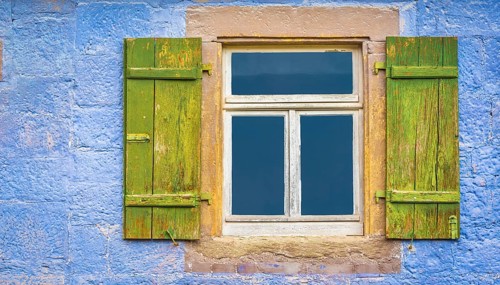 Aged wooden window and green shutters from an old german house with blueish painted wall stone