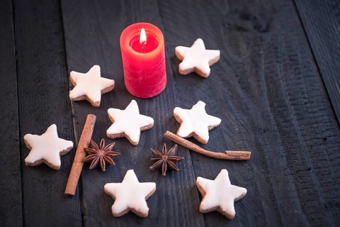 Homemade cinnamon and nuts cookies, star shaped, with decorative spices between them, on an old