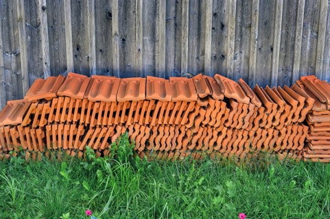 Stacked roof tiles in front of a wooden wall, Germany, Europe