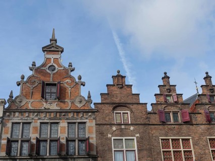 Historic brick buildings with ornate gables and red shutters against a blue sky, nijmegen, the