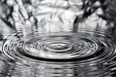 A drop of water causes concentric waves, circles and rings on the surface of the water