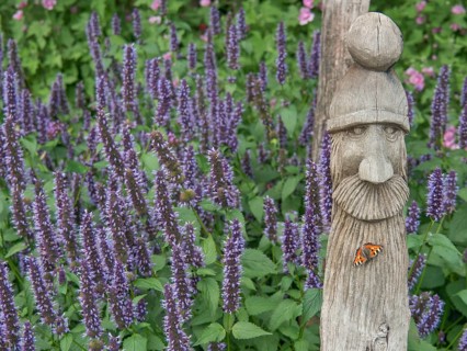 Wooden sculpture with a butterfly surrounded by purple flowering plants, papenburg, emsland,