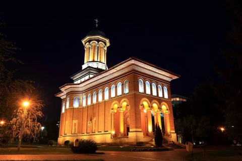 Illuminated church at night with a high tower, blue sky and visible windows. Craiova, Krajowa,