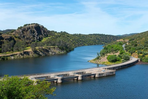 Large dam across a wide river, surrounded by hills and nature, River Tiétar, Tietar, right