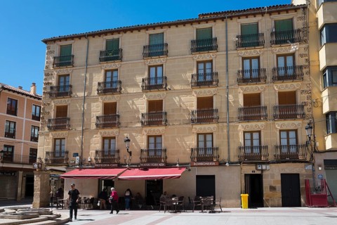 Historic building with balconies and shaded terrace, bright sunshine and clear sky, Plaza el Rosel,