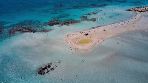 Overtourism, Aerial view of a sandbank in the sea with people swimming and relaxing in the clear