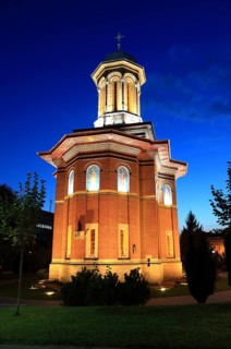 Illuminated church at night with a high tower, blue sky and visible windows. Craiova, Krajowa,