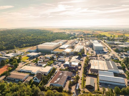 Industrial area with numerous buildings, streets and trees in a scenic setting under a clear sky,