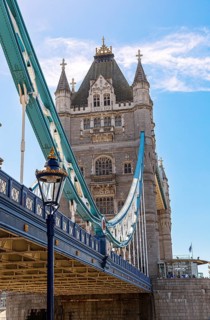 The historic Tower Bridge with towering structures and blue lower section under a clear sky,