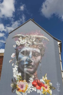 Portrait of a bigender person, bisexuality symbolised by horns and flower arrangement, mural by