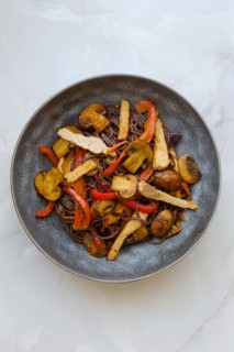 Overhead view of stir fried pork meat with mushrooms and black rice noodles