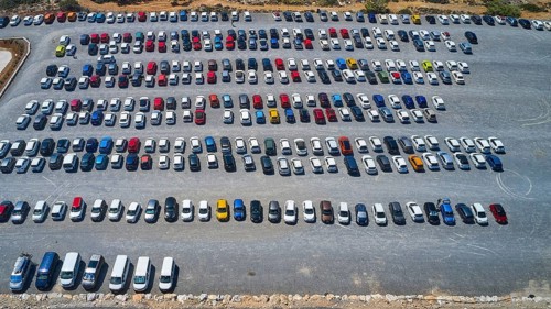 Overtourism, aerial view of a large car park with numerous vehicles parked in order, in sunny