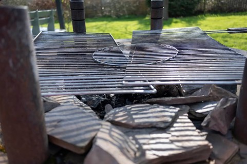 Outdoor barbecue, barbecue from an old well, two used grill grates lying on top, burnt coal