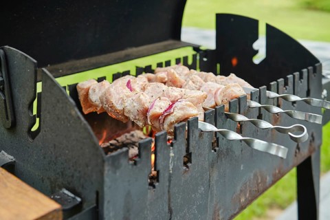 Cooking skewered pork meat on barbecue, close-up view