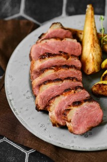 Close-up view of seared duck breast with golden-brown roasted potato wedges
