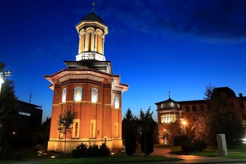 Illuminated church at night with a high tower, blue sky and visible windows. Craiova, Krajowa,