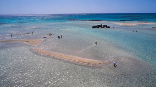 Sandbank in clear, calm sea with scattered people enjoying the natural surroundings, Elafonissi,