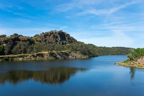 River with large rock in the background and blue sky, landscape characterised by natural wonders,