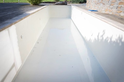 Outdoor pool, empty, light-coloured walls, in the garden on a wooden terrace, light and shade,