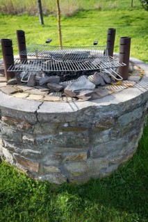 Outdoor barbecue, barbecue from an old well, two used grill grates lying on top, four metal pipes