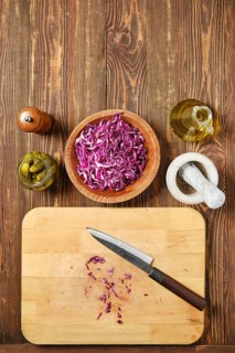 Overhead view of kitchen tabletop with red cabbage and pickled cucumbers