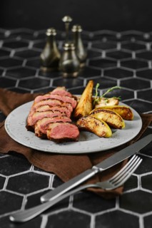 A succulent duck breast is perfectly seared and surrounded by tender, caramelized apple and pear