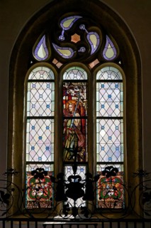 Interior view, Gothic church window with richly decorated stained glass and a figure of a saint in