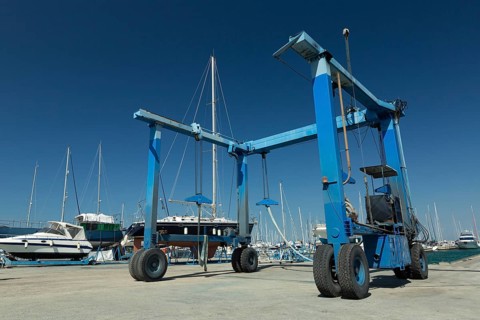 Blue lifting crane for elevating boat and maintenance machine at harbor dock