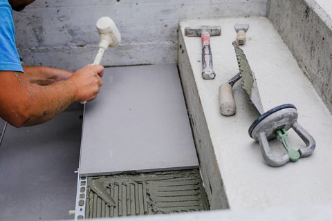 Tiler hands working on a new house entrance, local and professional handyman applying tiles to the