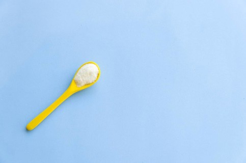Spoon with sugar close-up on a light blue background