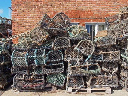 Lobster pots used in traditional fishing for crustaceans stacked against a building in scarborough