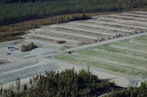 Digger excavating land to make humps and hollows for farmland, West Coast, South Island, New