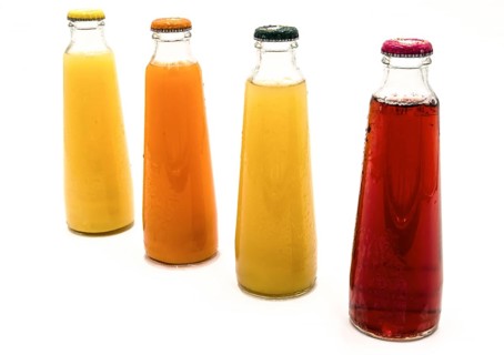 Four bottles of fruit juice, cherry, orange, pineapple, multifruit on a white background