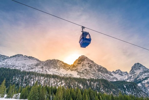 Cable car route going over the Austrian alps mountains with their fir forests, while the sun sets