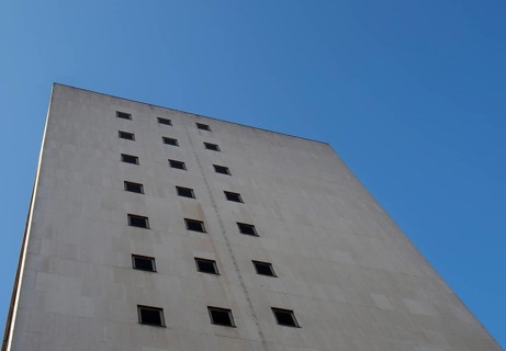 Perspective corner view of an old white 1960s concrete office block against a blue sky