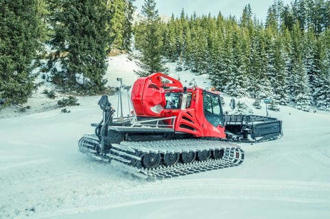 Winter image with a modern snow groomer machine, captured in the Austrian Alps, near the village
