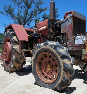 A rusting and corroded old tractor is parked on a sand beach