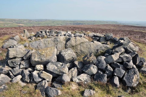 The exposed stones at the top of a cairn known as the millers grave on midgley moor in calderdale