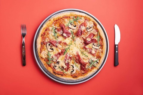 Homemade pizza with prosciutto crudo, arugula, mozzarella and champignons. Flat lay with a ham