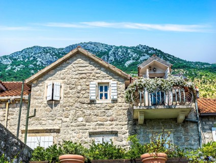 Old house with flowers on balcony in Perast, Montenegro, Europe