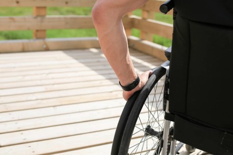 Disabled young man on a wheelchair holding and turning wheels with hand