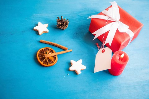 Gift, wrapped in red paper and tied with white ribbon and bow, with a blank tag attached to it,