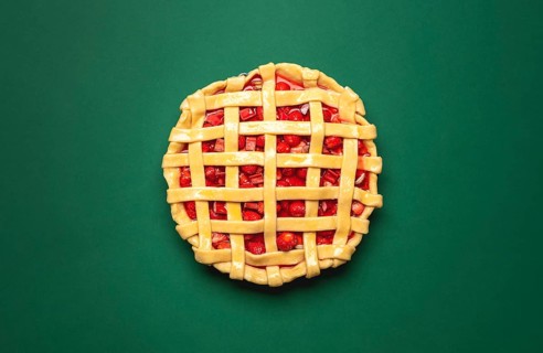 Strawberries and rhubarb pie with a lattice crust, above view on a green background. Top view with