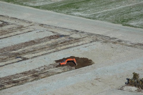 Digger excavating land to make humps and hollows for farmland, West Coast, South Island, New